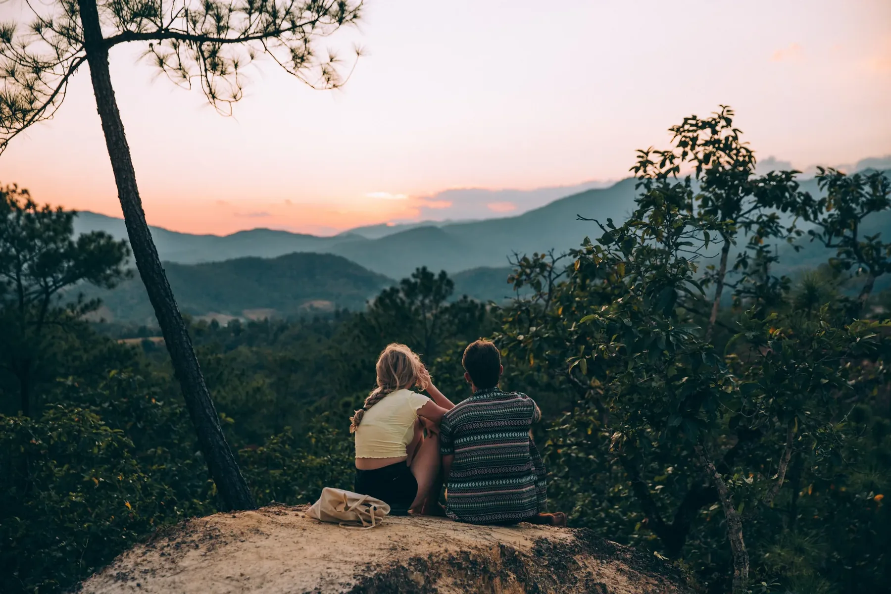 Couple watching the sunset over a forested landscape on a romantic Uganda honeymoon safari